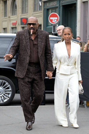 Steve Harvey With A Cigar And His Wife Wallpaper