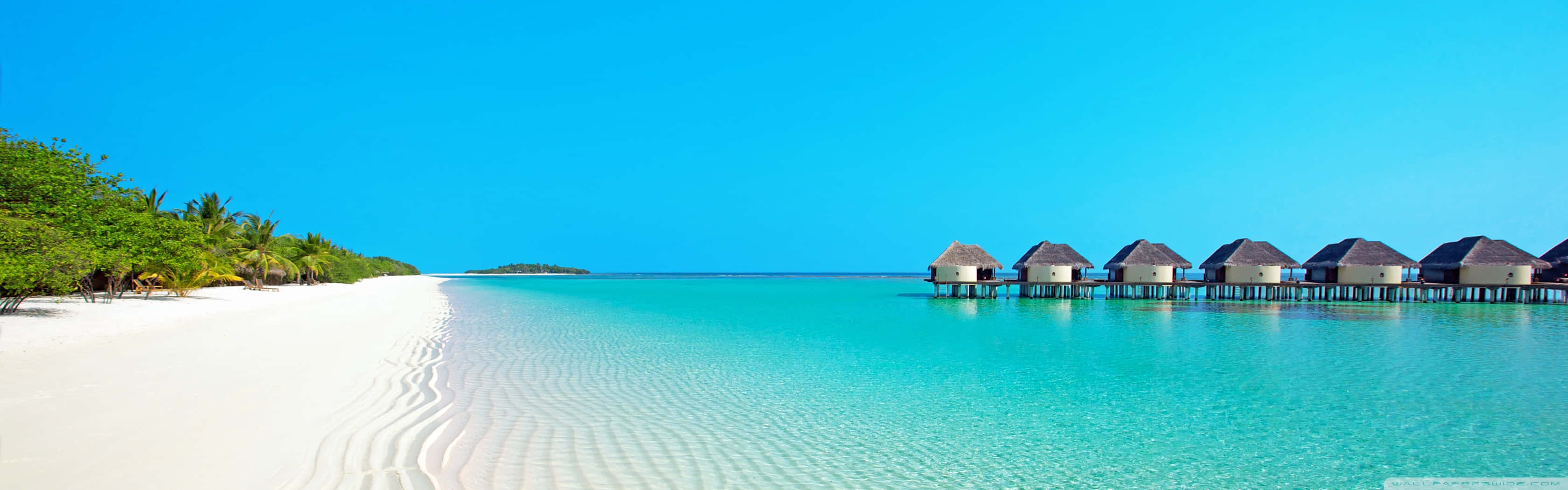 A Beach With White Huts And Clear Water
