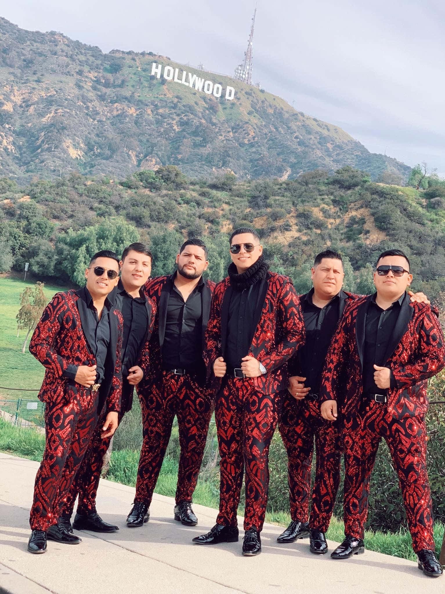 A Group Of Men In Suits Standing In Front Of The Hollywood Sign
