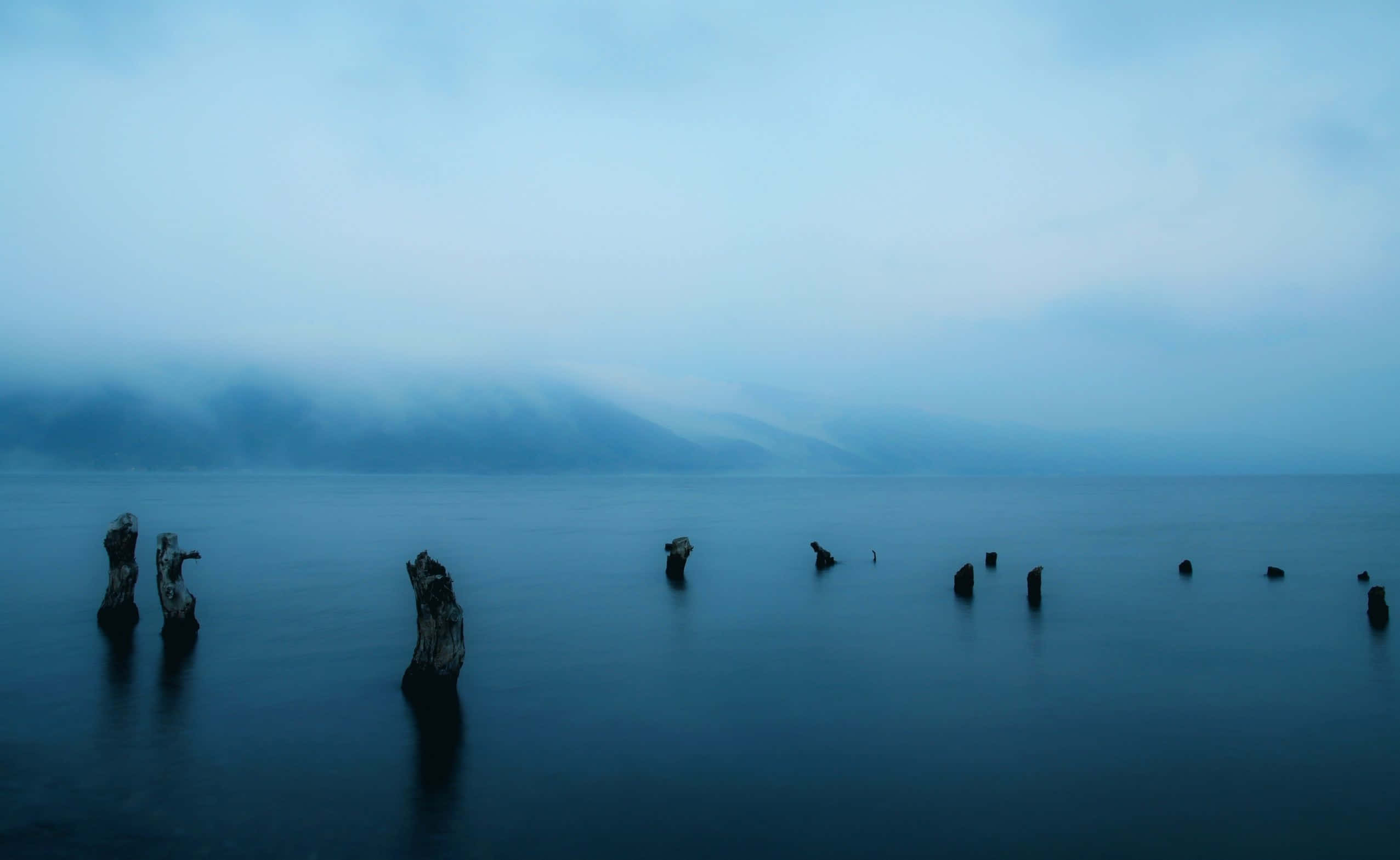 A Lake With Some Old Wooden Posts In The Water