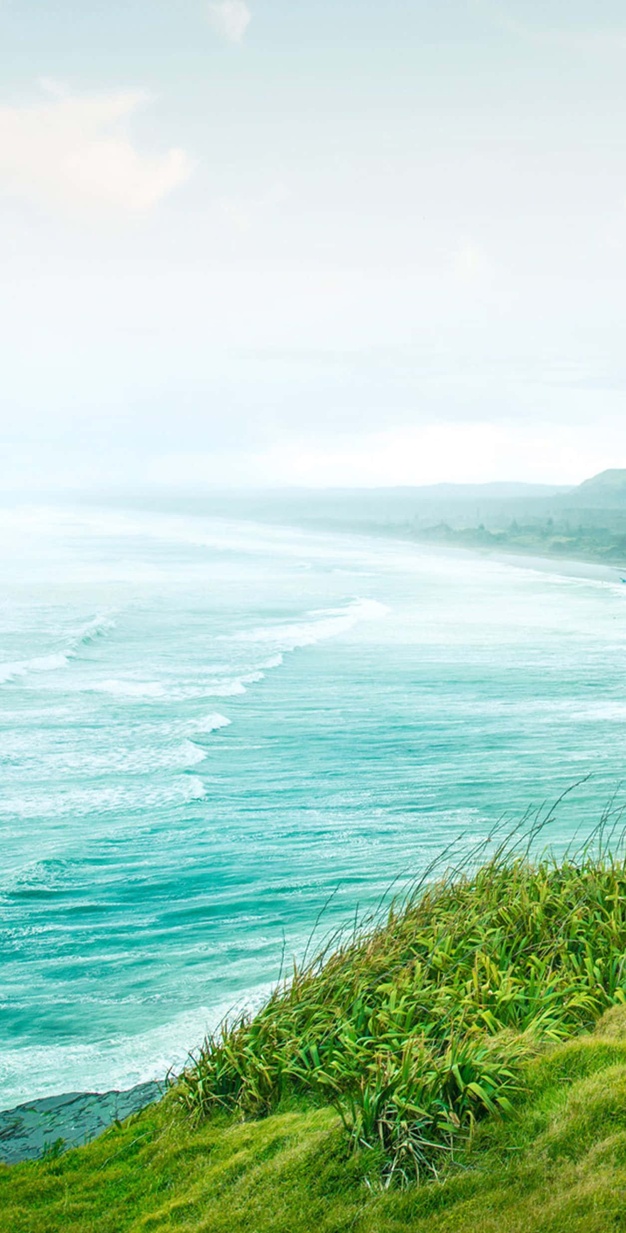A Man Is Standing On A Hill Overlooking The Ocean