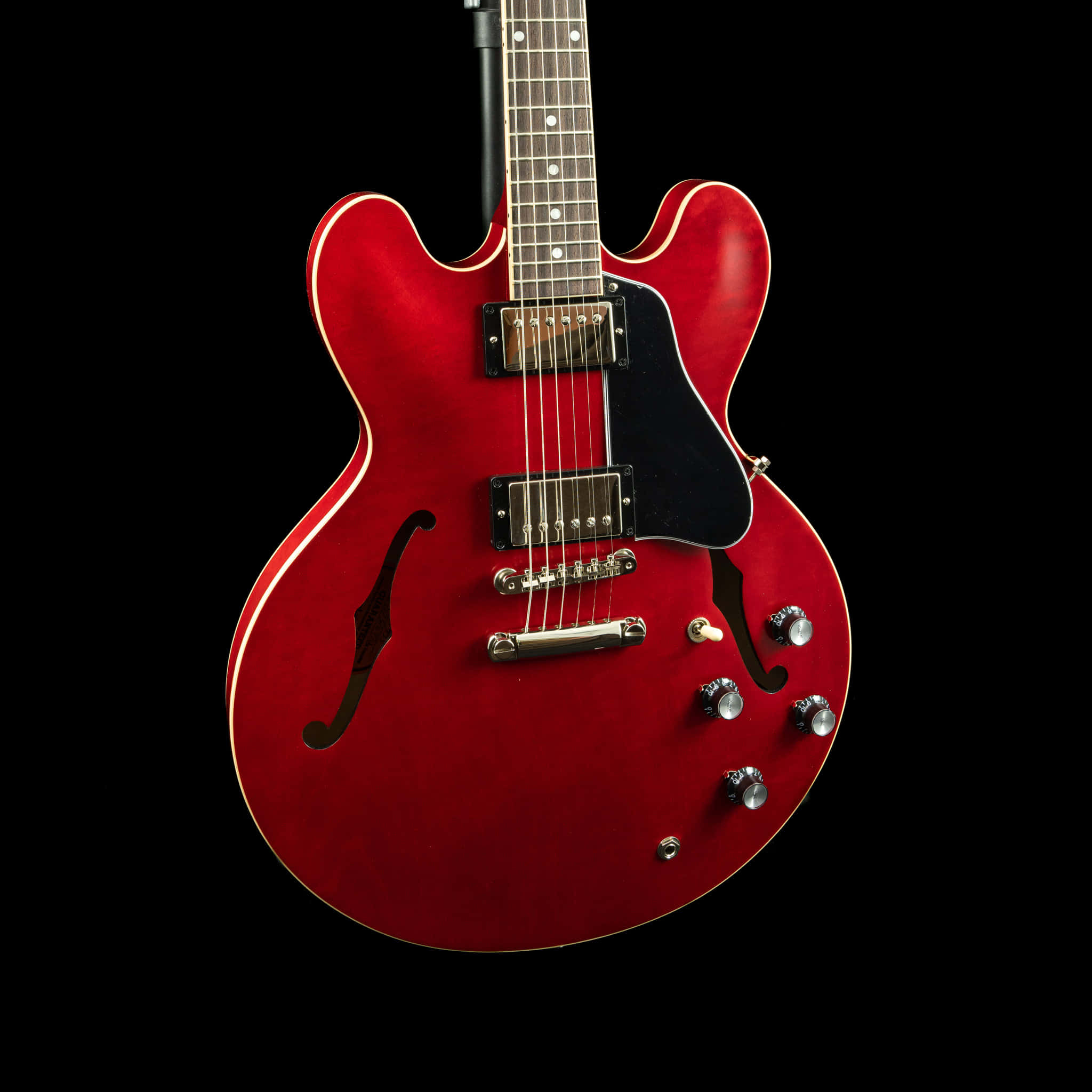 A Red Electric Guitar Is Shown Against A Black Background