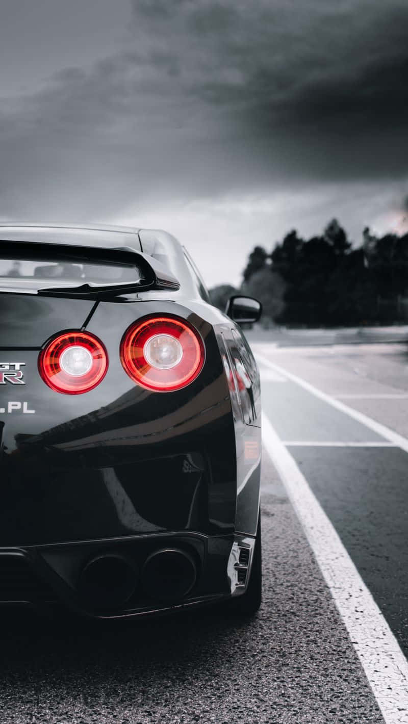 A Black Sports Car Is Parked On A Road Wallpaper