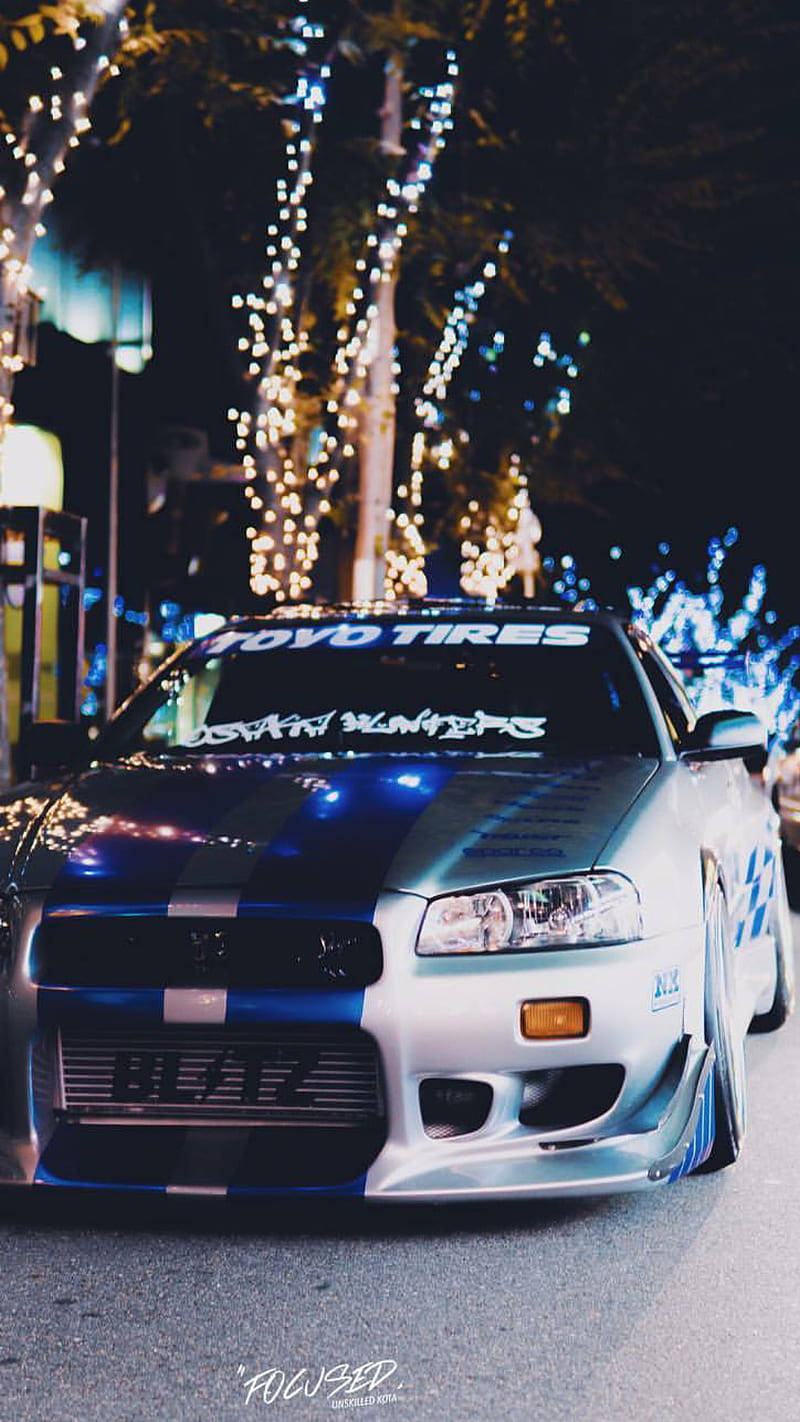 A Blue And White Car Parked In The Street At Night Wallpaper