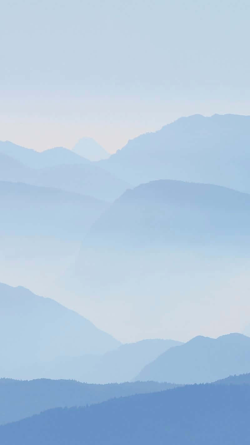 A Blue Sky With Mountains In The Background Wallpaper