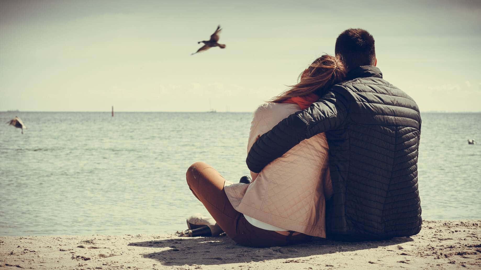 A Couple Enjoying Sunset View On Beach Wallpaper