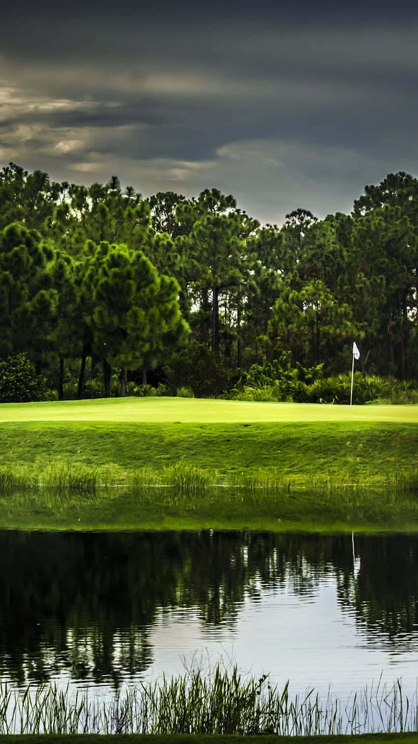 A Golf Course With A Pond And Trees Wallpaper