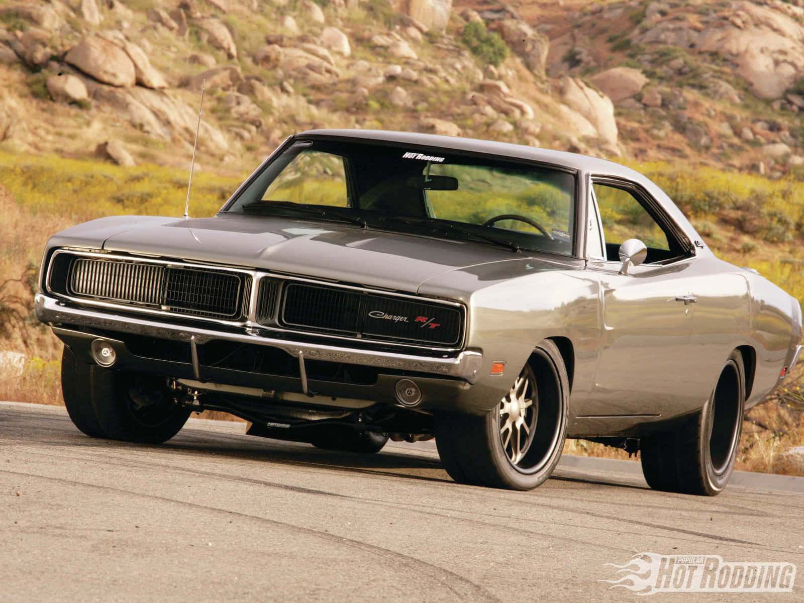 A Gray Muscle Car Driving Down A Road Wallpaper