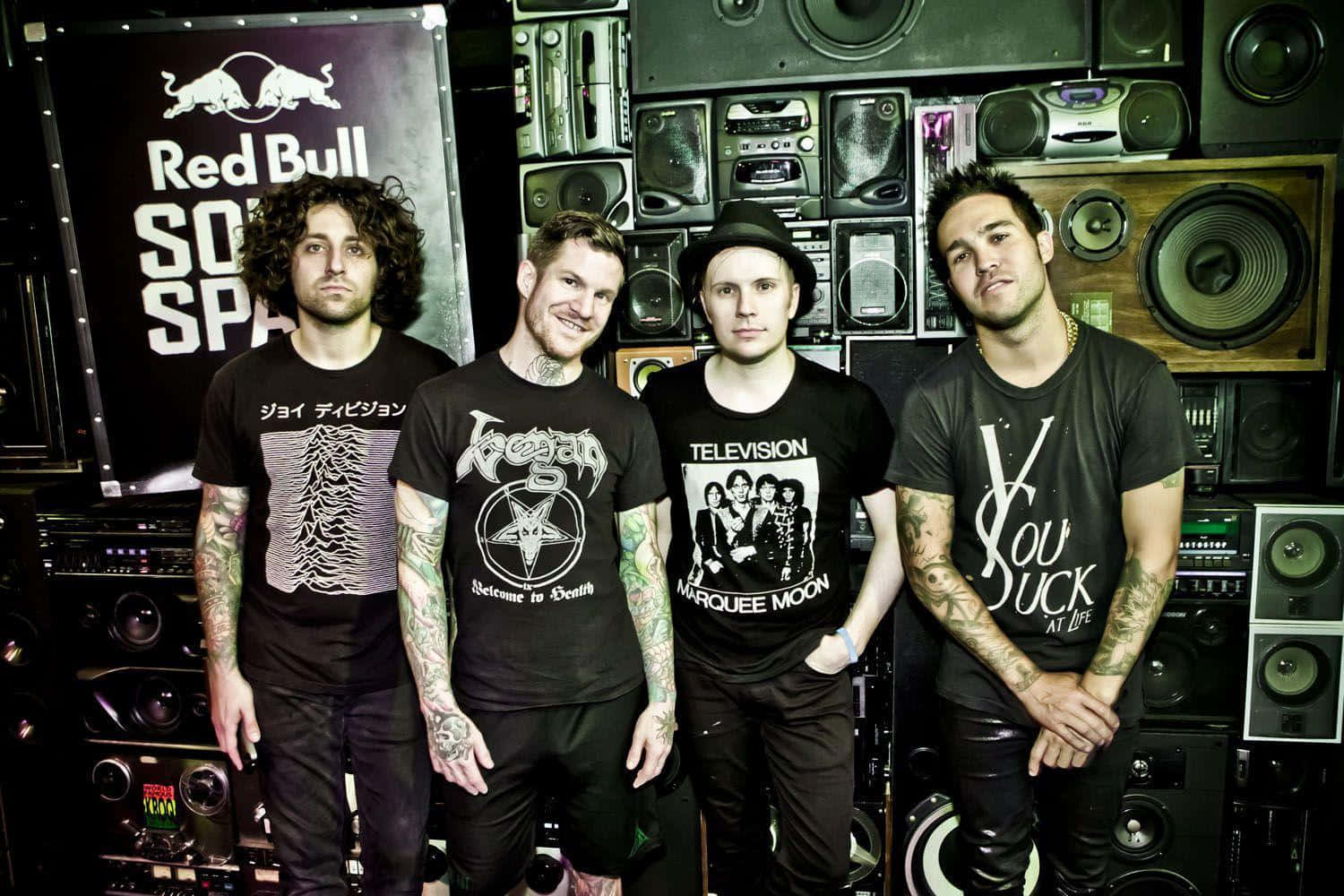 A Group Of Men Standing In Front Of A Speaker Wallpaper