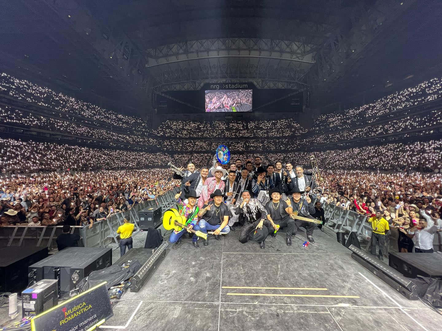 A Group Of People Posing On Stage In A Large Stadium Wallpaper