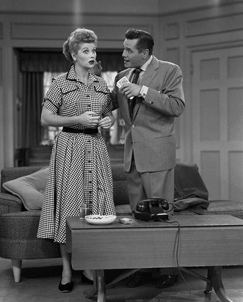 A Man And Woman Standing In Front Of A Couch Wallpaper