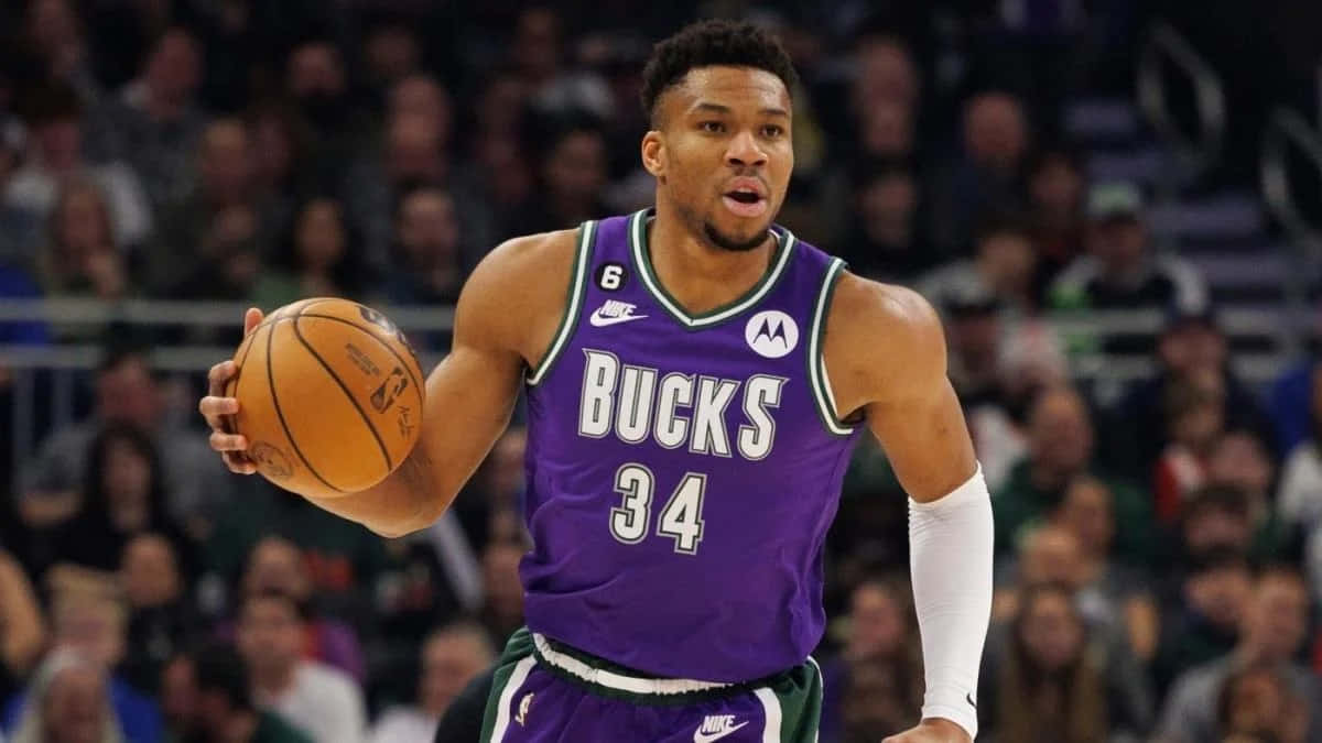 A Man In Purple Uniform Is Holding A Basketball Wallpaper