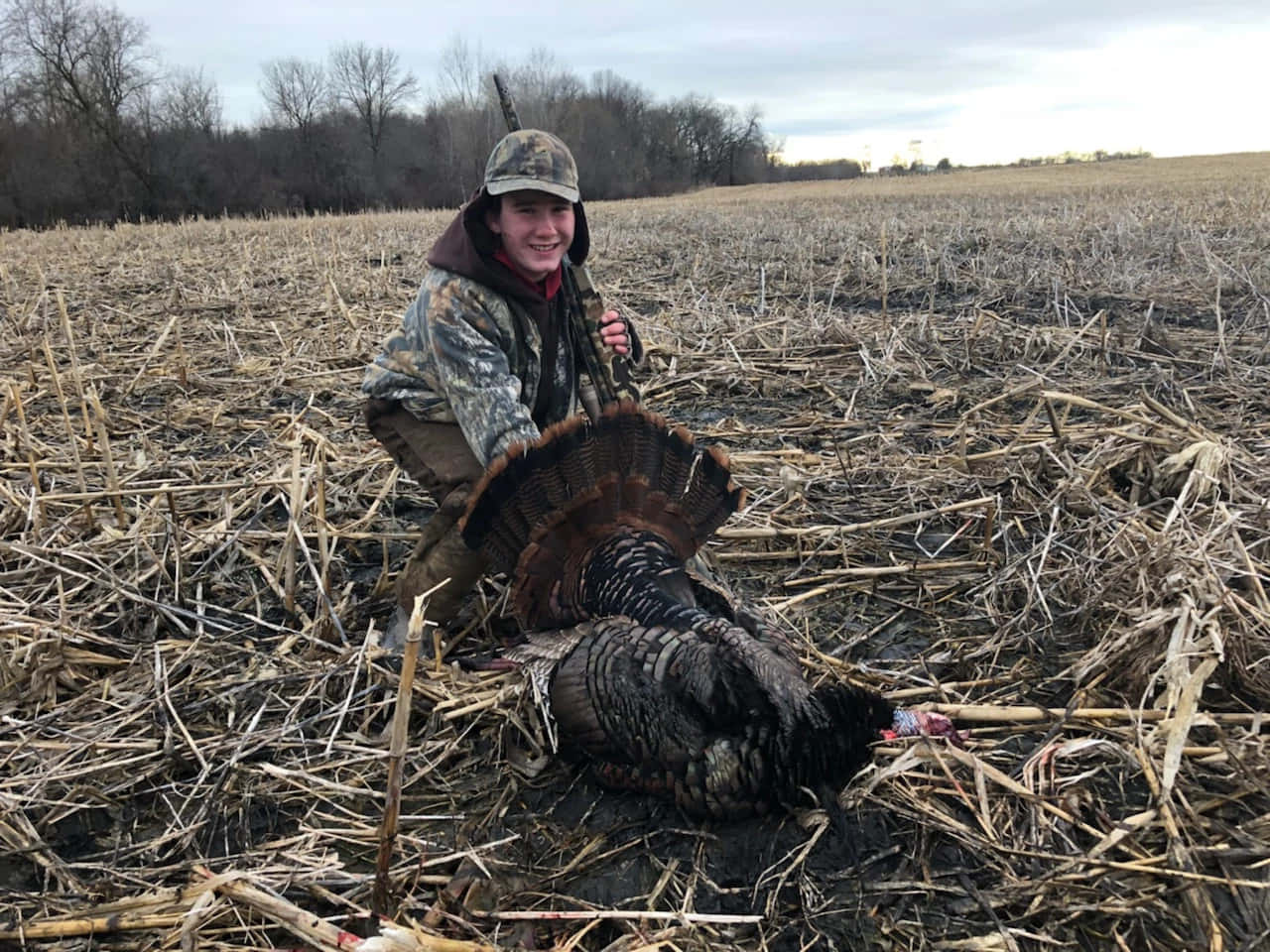 A Man Kneeling Down In A Field With A Turkey Wallpaper