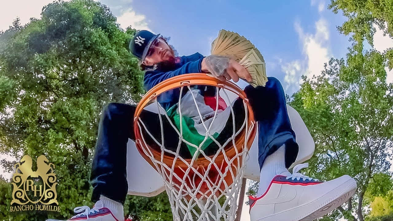 A Man Sitting On Top Of A Basketball Hoop Wallpaper