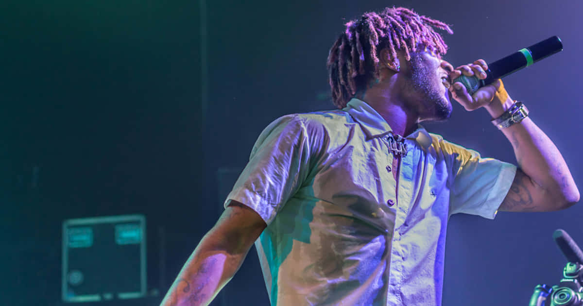 A Man With Dreadlocks Singing Into A Microphone Wallpaper