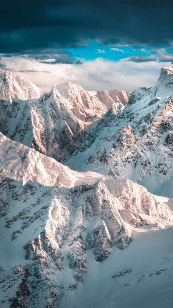 A Snow Covered Mountain Range With Clouds In The Sky Wallpaper