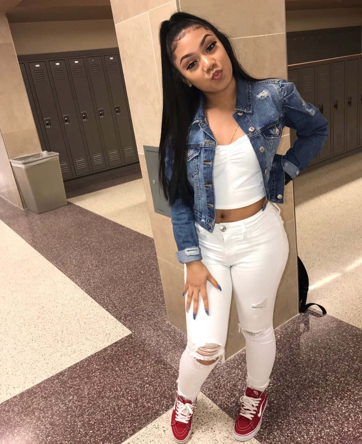 A Woman In White Jeans And Red Sneakers Posing In A Hallway Wallpaper