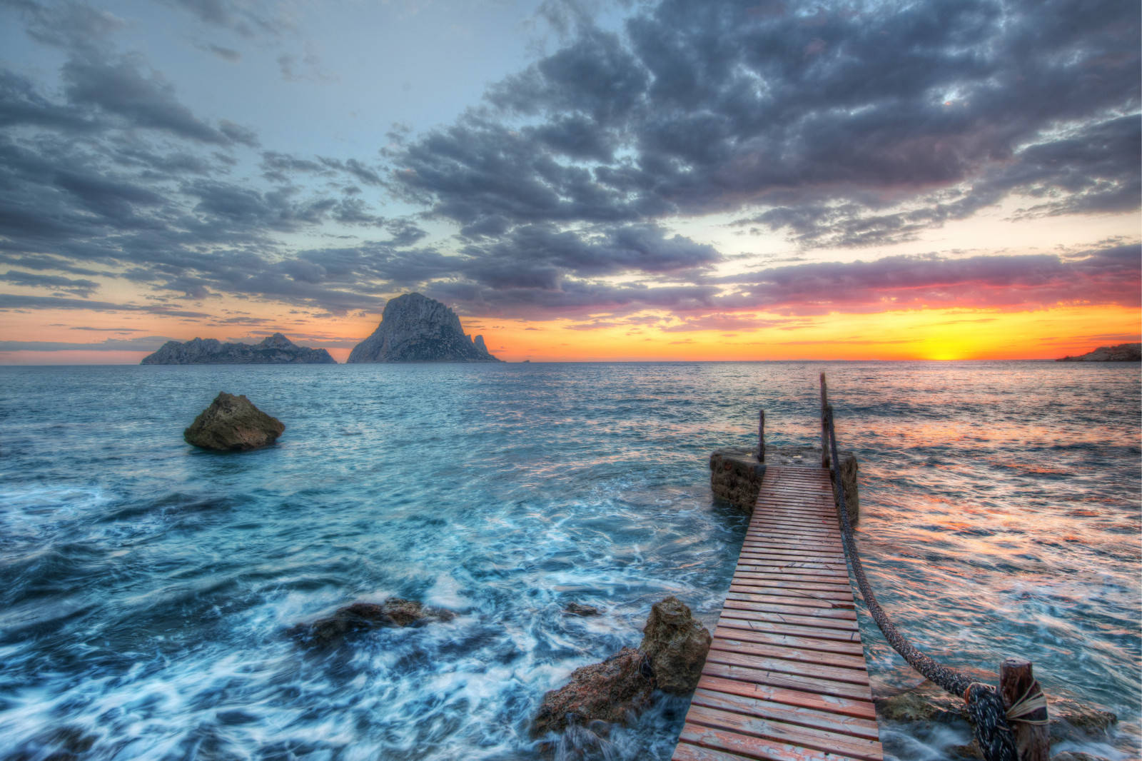 A Wooden Pier In The Ocean At Sunset Wallpaper