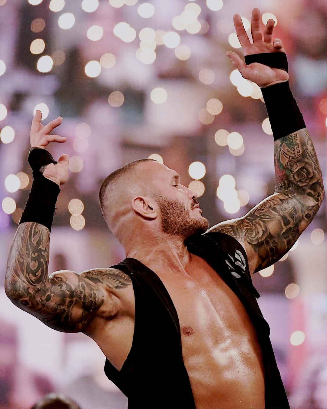 A Wrestler With Tattoos Is Holding His Hands Up Wallpaper