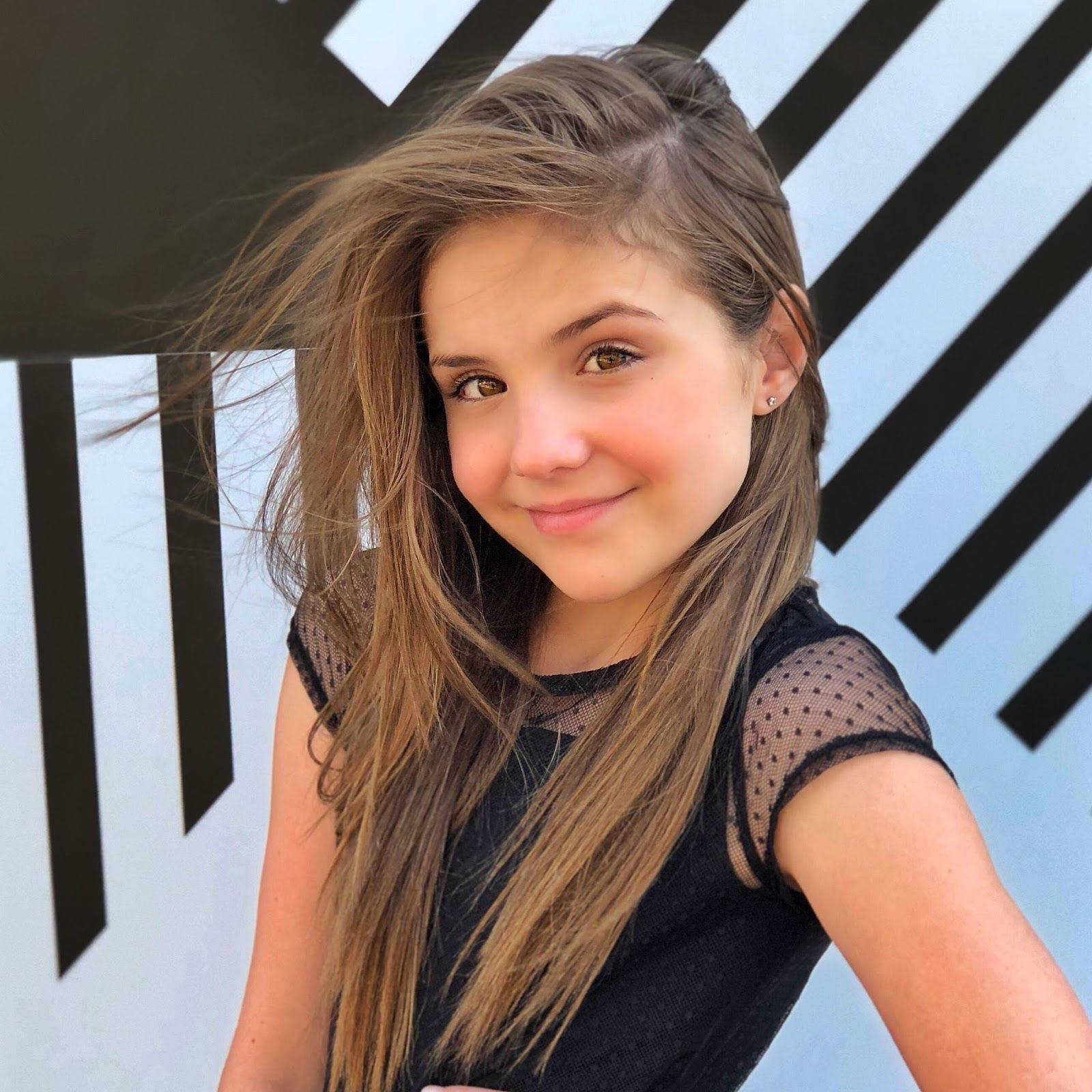 A Young Girl In A Black Dress Posing For A Photo Wallpaper