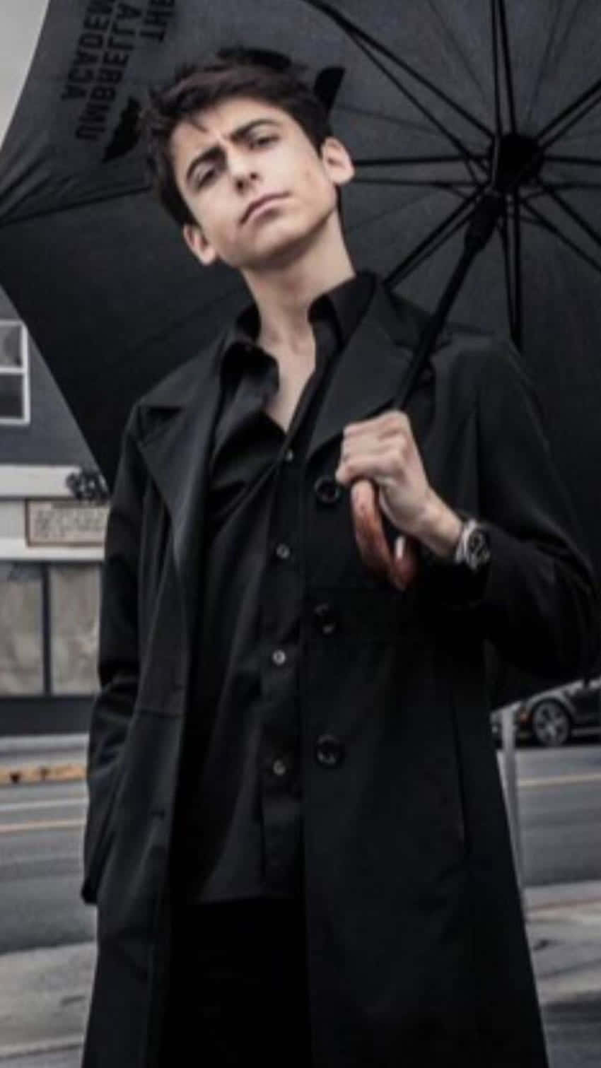 A Young Man Holding An Umbrella On The Street Wallpaper