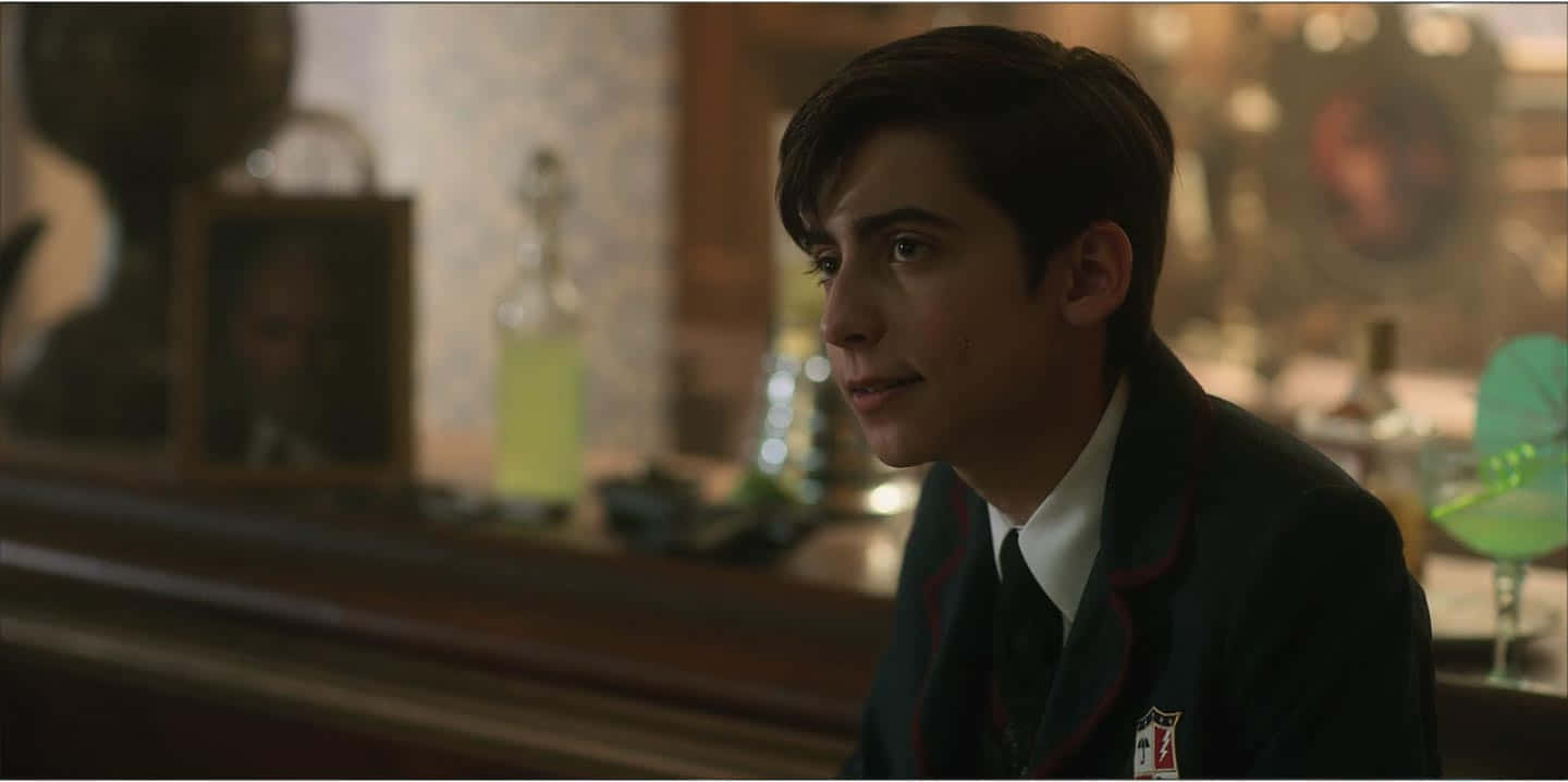 A Young Man In A School Uniform Sitting At A Bar Wallpaper