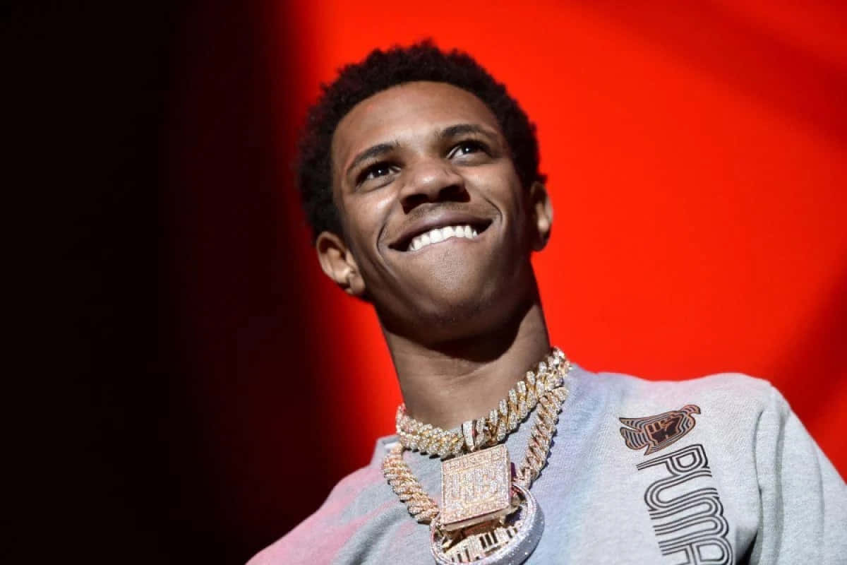 A Young Man Is Smiling While Wearing A Necklace Wallpaper