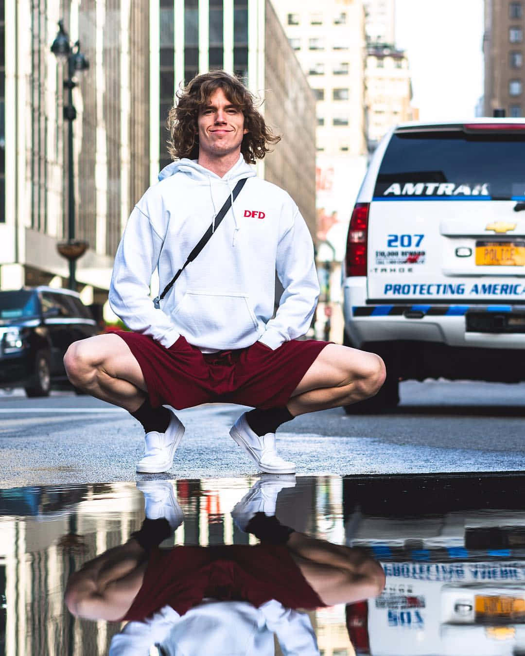 American Celebrity Danny Duncan Squatting Near Puddle Wallpaper