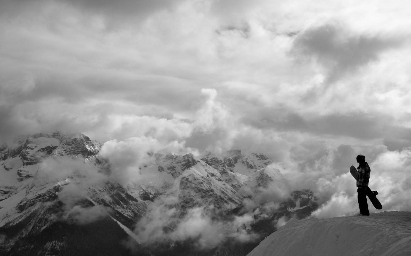 Black And White Man With Snowboard Looking Down Wallpaper