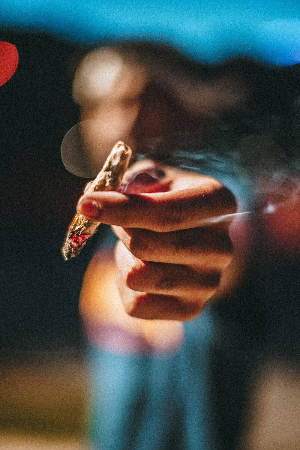 Blurry Man Holding Blunt Outdoors Wallpaper