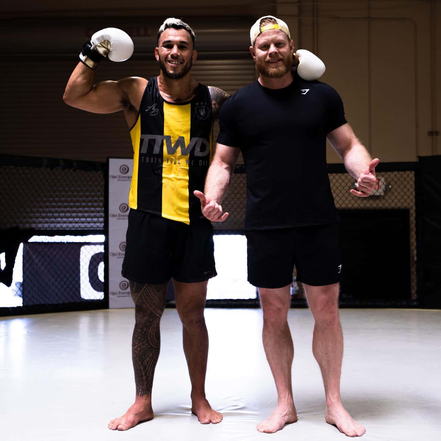 Brad Tavares Flexing Muscles Alongside A Fellow Fighter Wallpaper