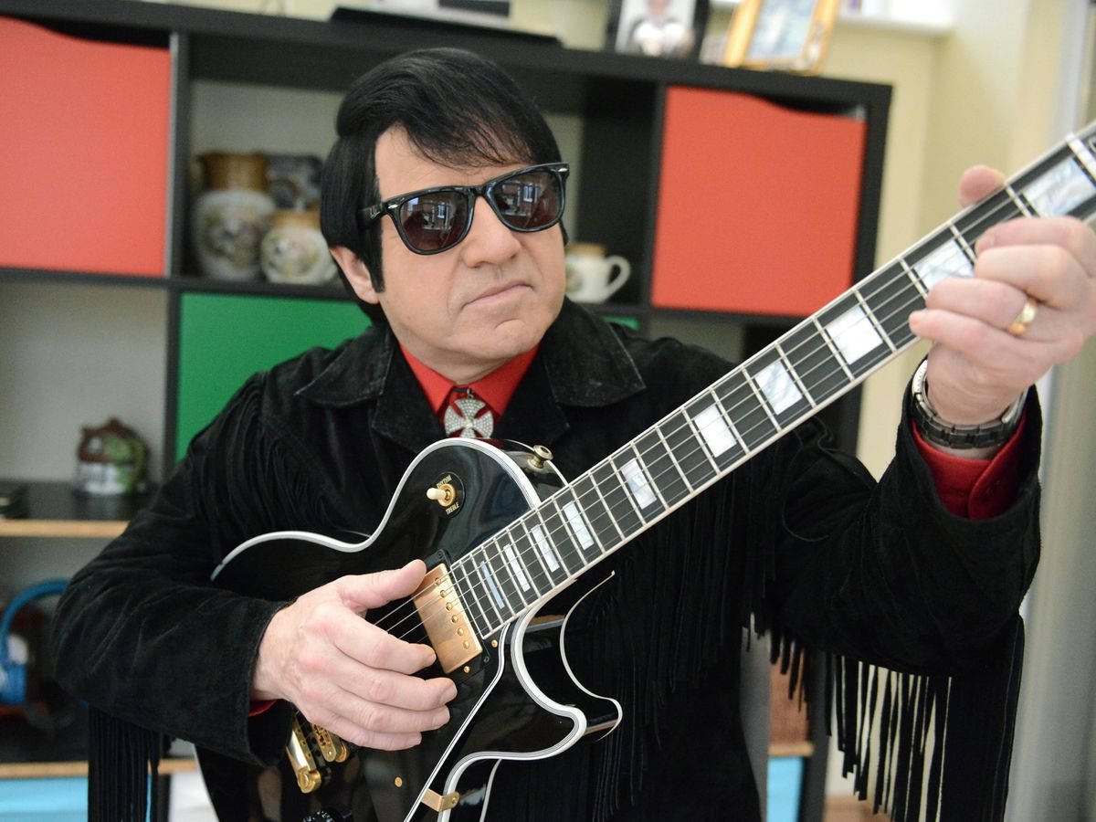 Caption: Iconic Musician Roy Orbison Masterfully Playing His Guitar Wallpaper