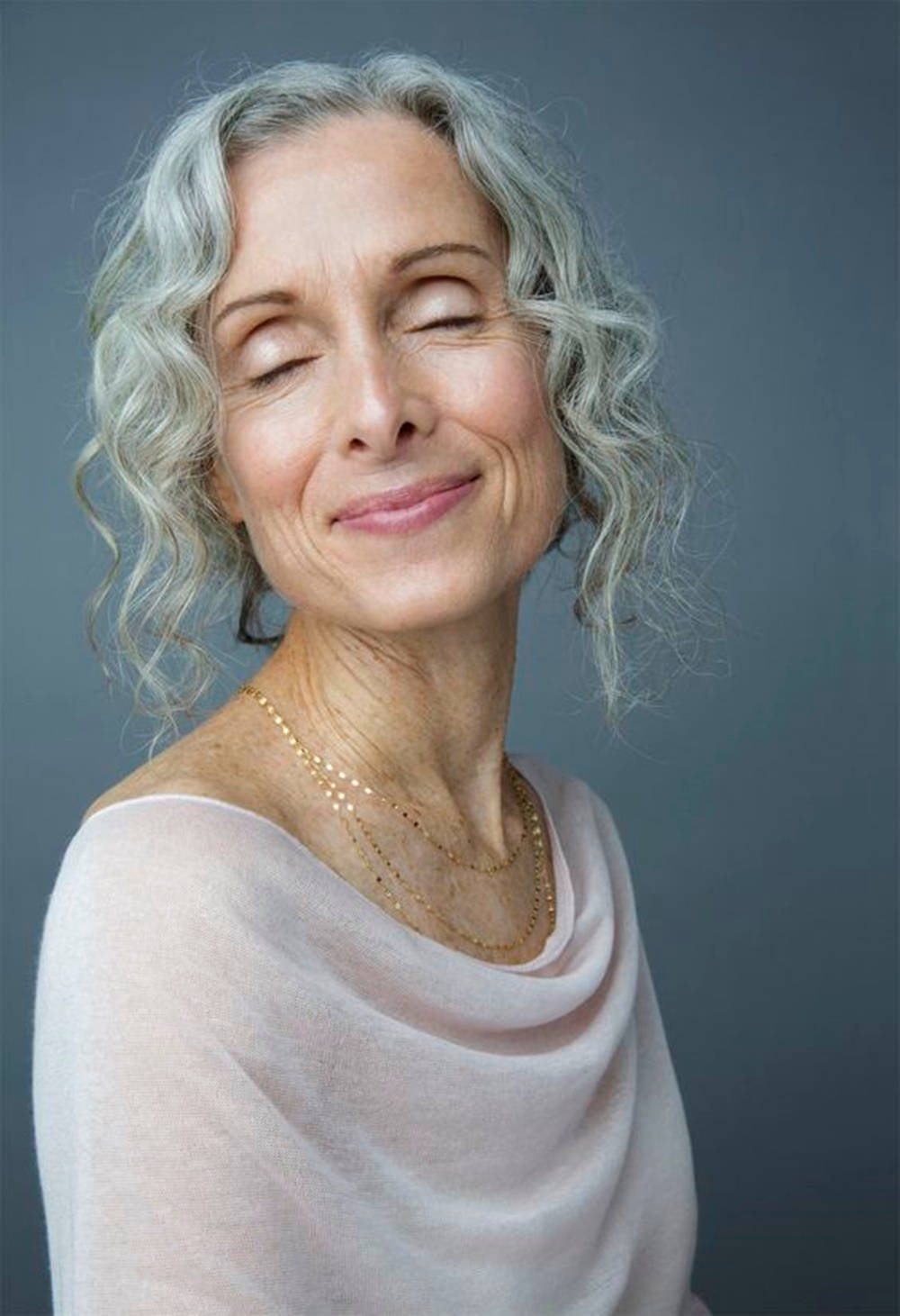 Caption: Spirited Senior Woman With Voluminous Curly Hair Wallpaper