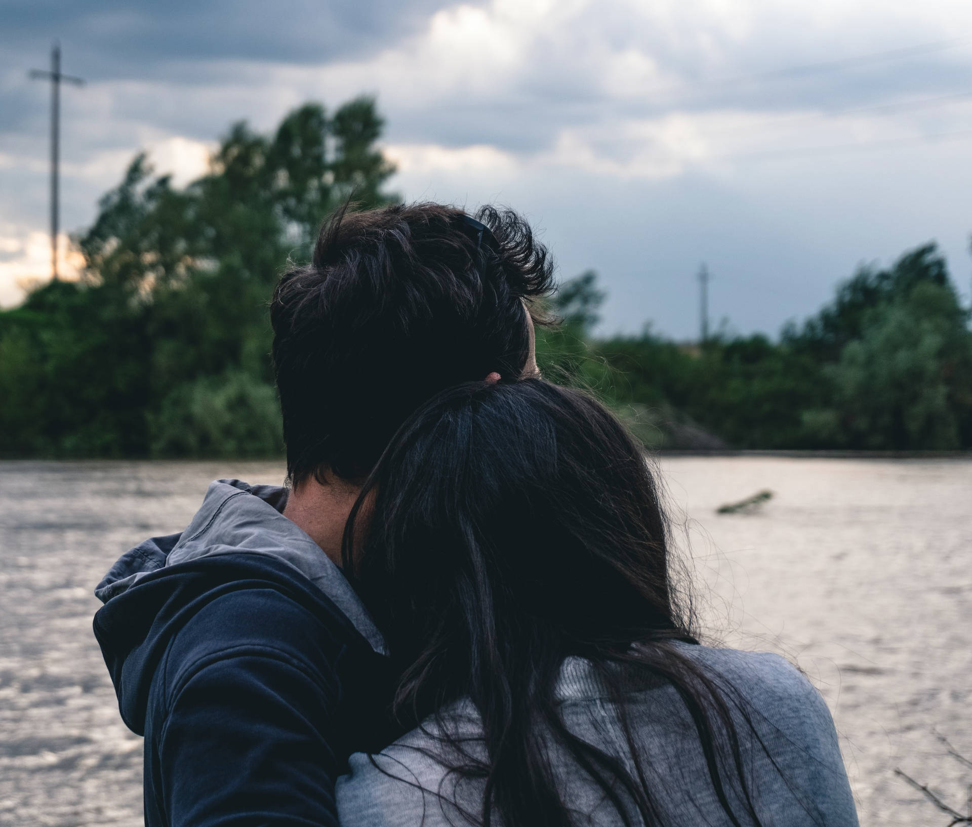 Couple Hugging By The Riverside Wallpaper