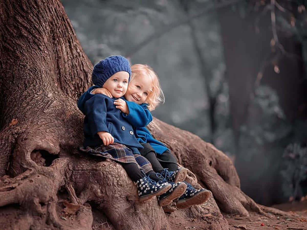 Cute Baby Couple Hugging Under The Tree Wallpaper