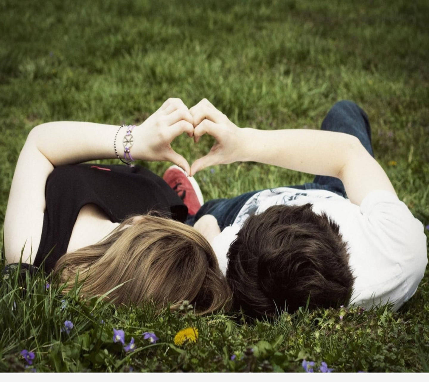 Cute Couple Making Cute Heart On Grass Wallpaper