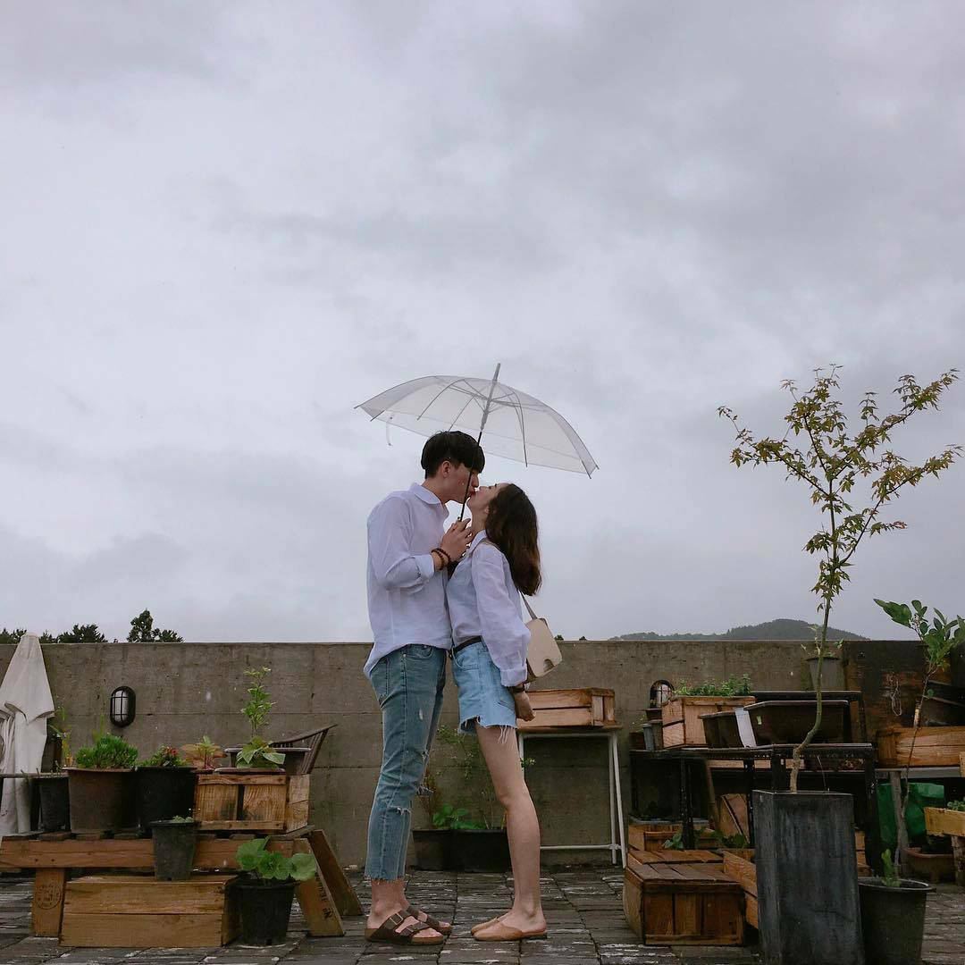 Cute Couple With Umbrella At A Rooftop Cafe Wallpaper
