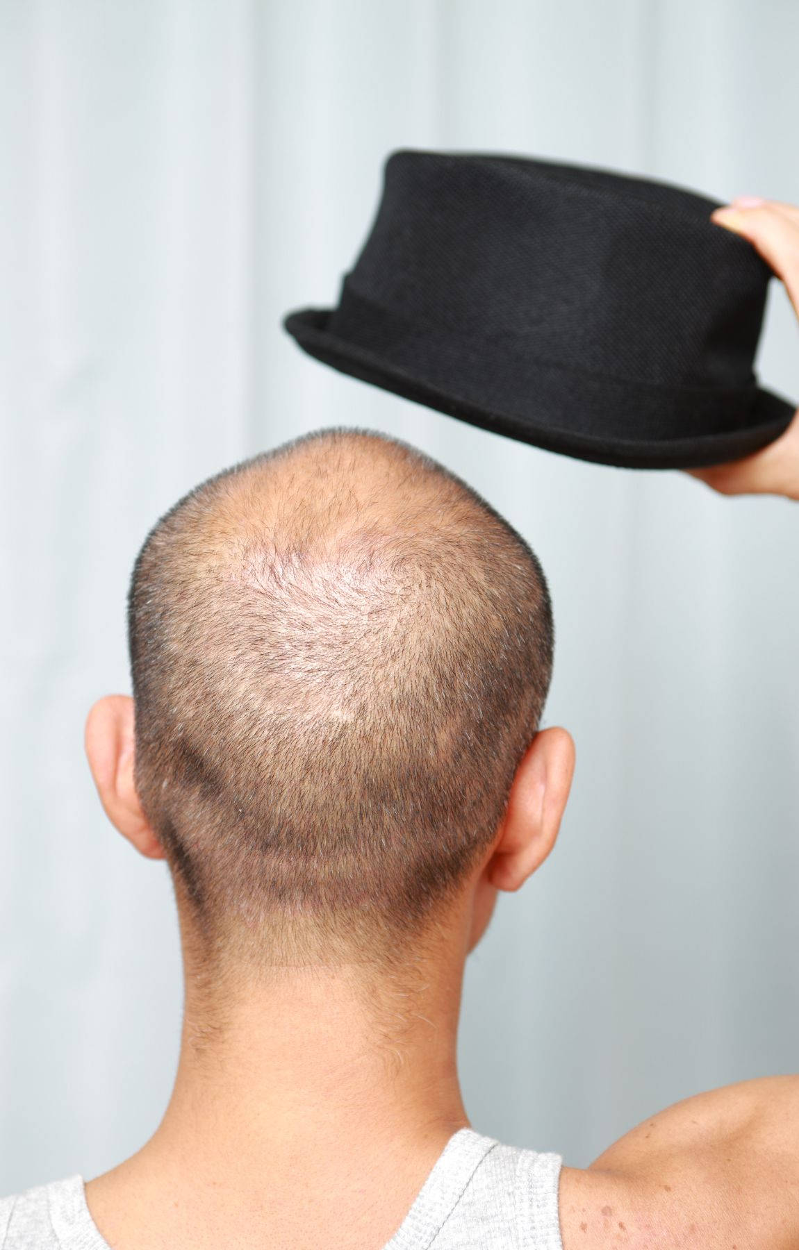 Debonair Bald Gent Holding Black Hat Wallpaper