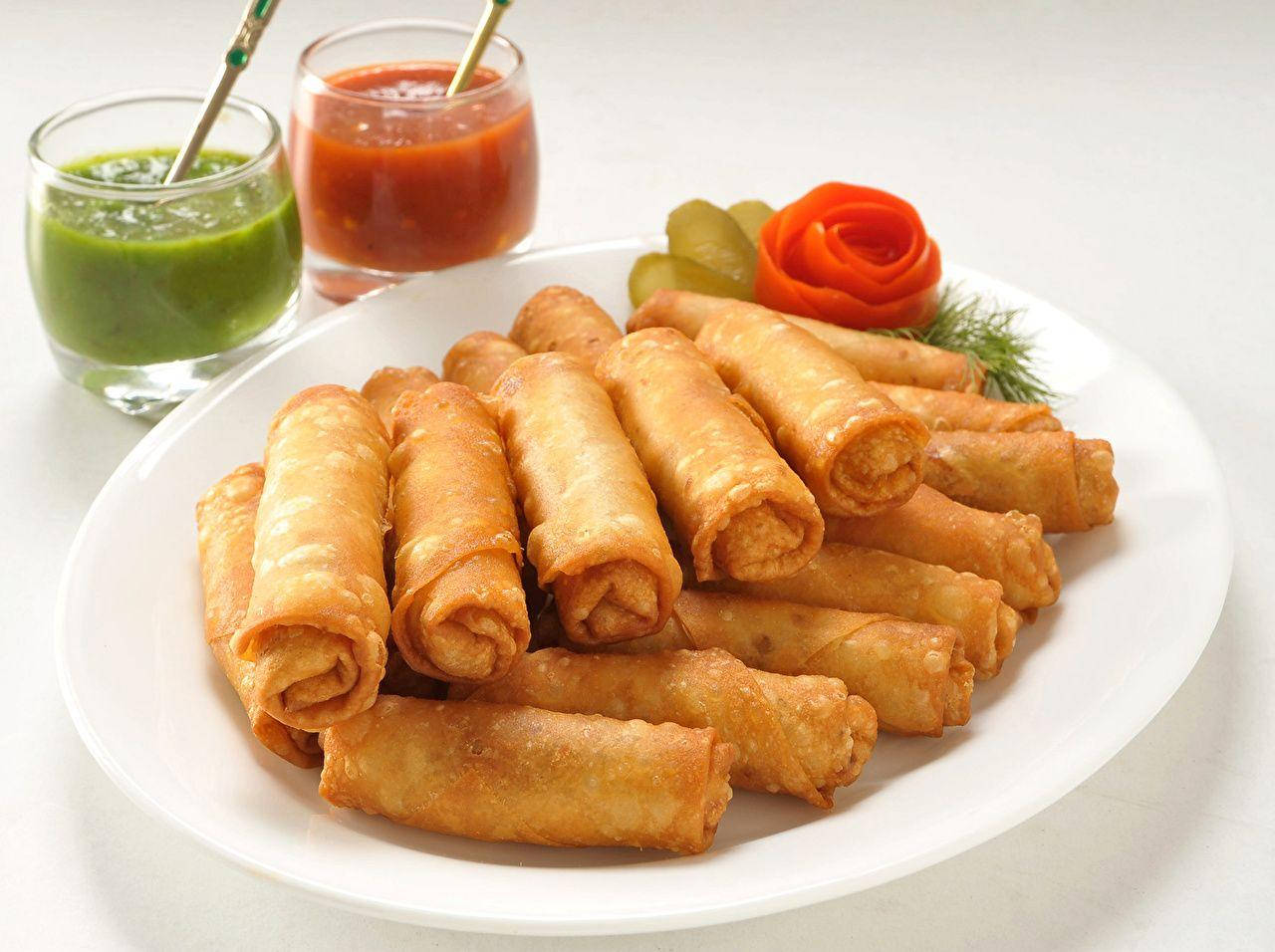 Delicious Stack Of Egg Rolls With Salsa Dips Wallpaper