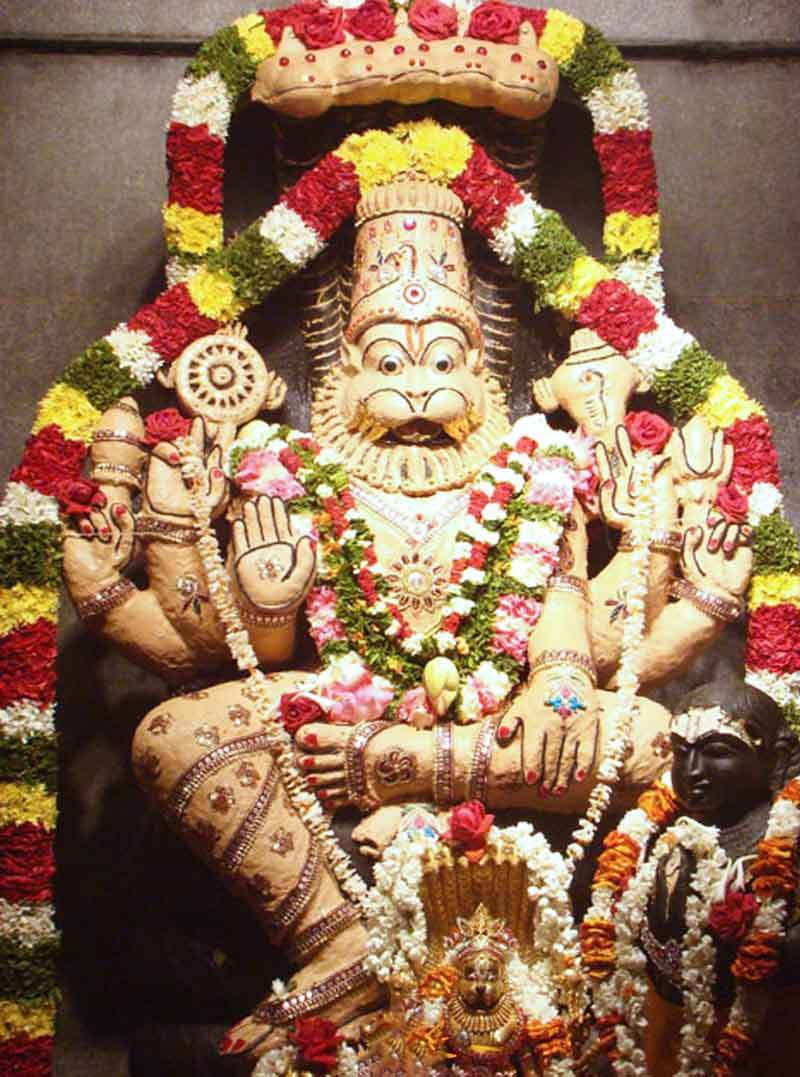 Divine Narasimha Statue Adorned With Vibrant Flowers Wallpaper