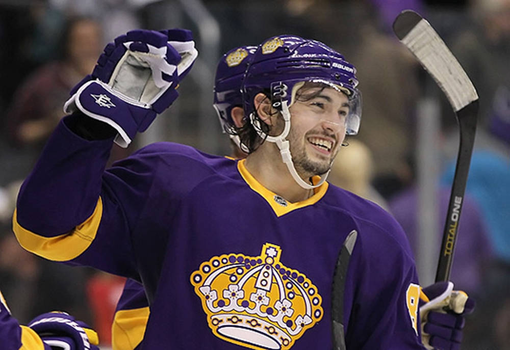 Drew Doughty Smiling While Wearing Vintage Jersey While Holding Hockey Stick Wallpaper