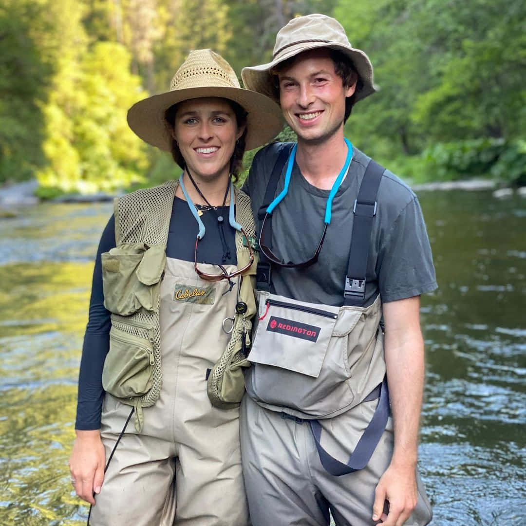 Fishing Adventure Couple Riverbank Wallpaper