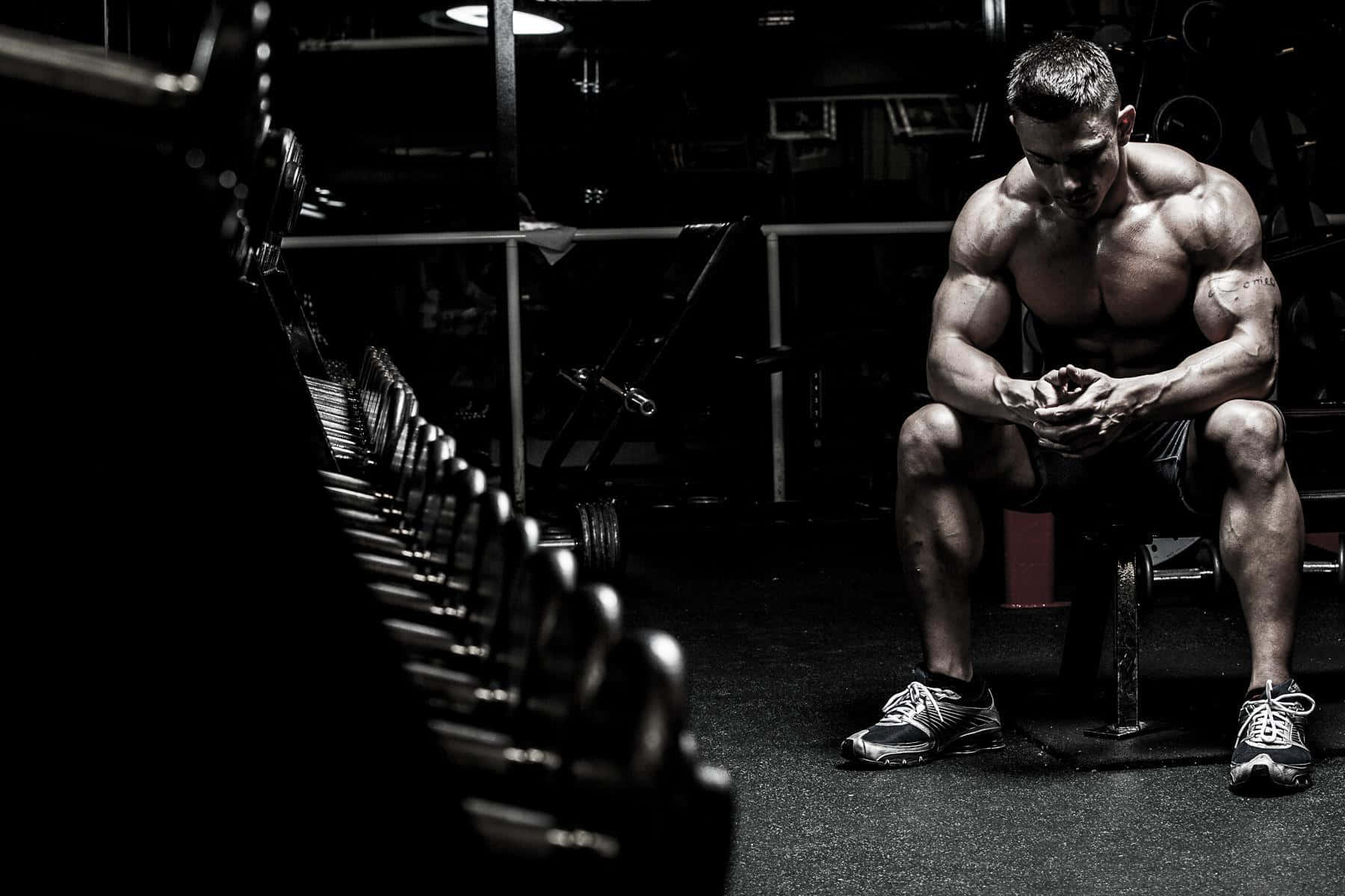 Focused Muscular Man Resting Gym Workout Wallpaper