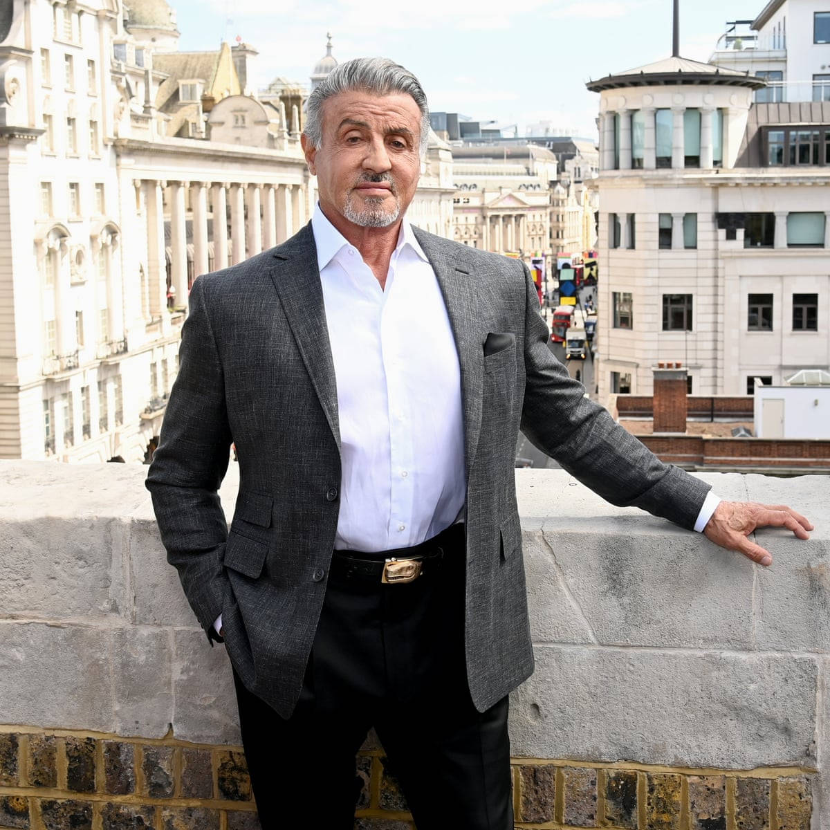 Hollywood Legend Sylvester Stallone Leaning On Concrete Wall Wallpaper