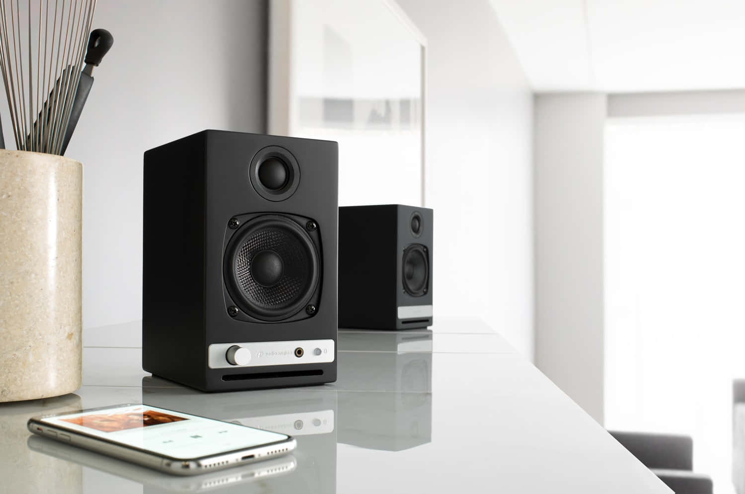 Modern Wireless Speakers Paired With White Smartphone Wallpaper