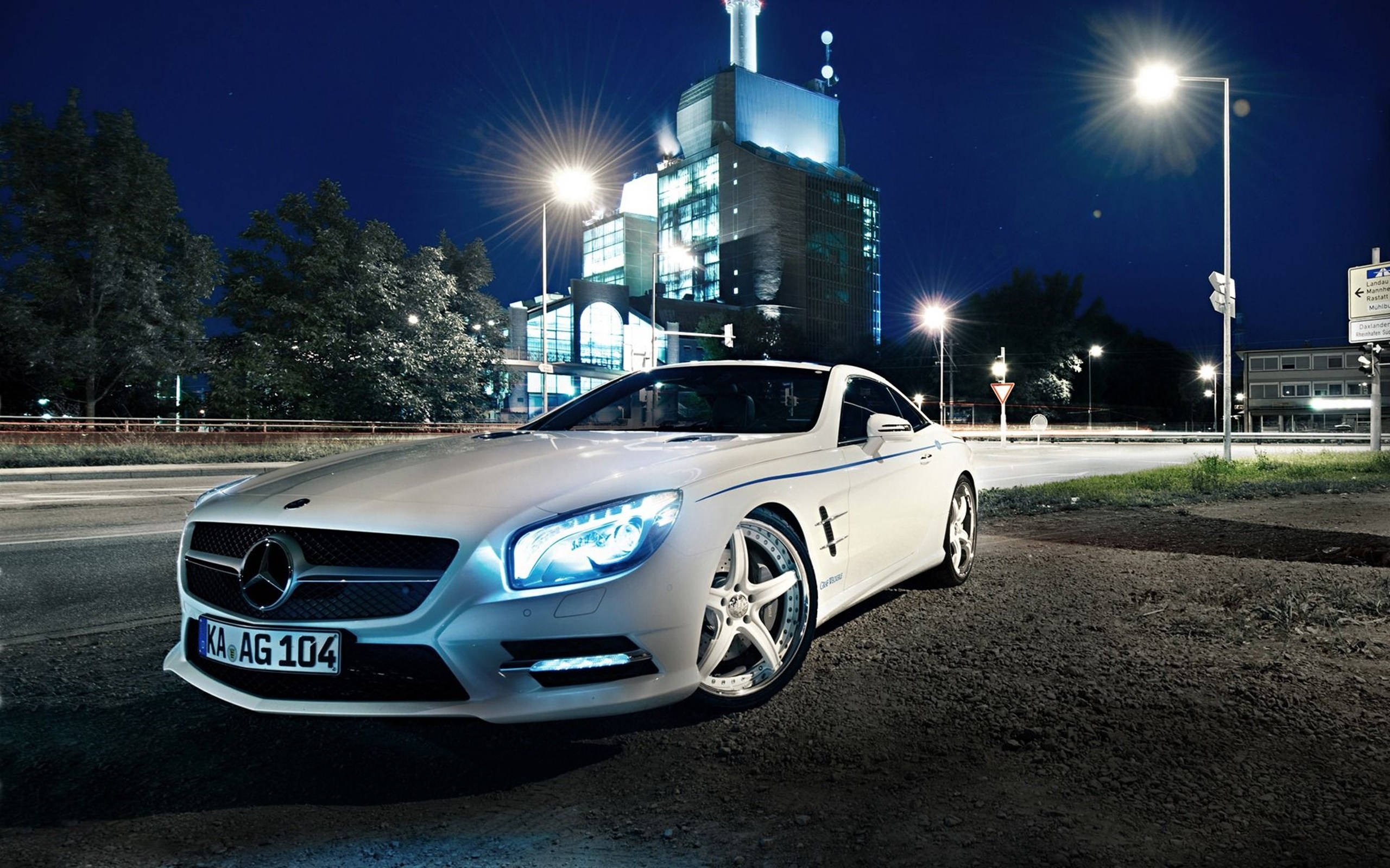 Night Life Luxury: White Mercedes Benz Under City Lights Wallpaper