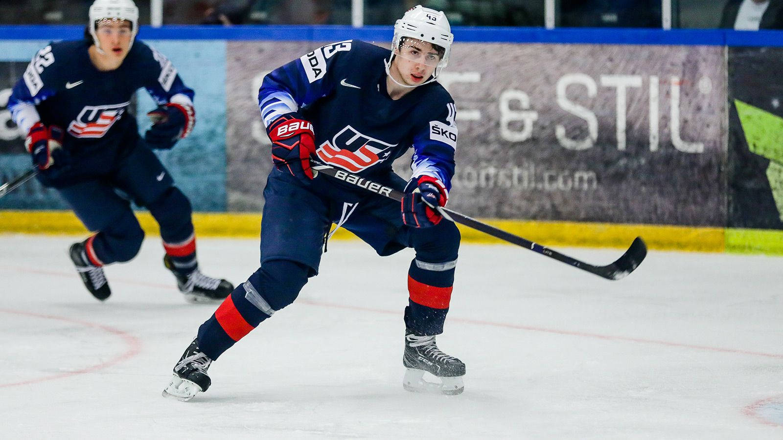 Quinn Hughes Leaning Forward And Holding Hockey Stick To The Left Wallpaper