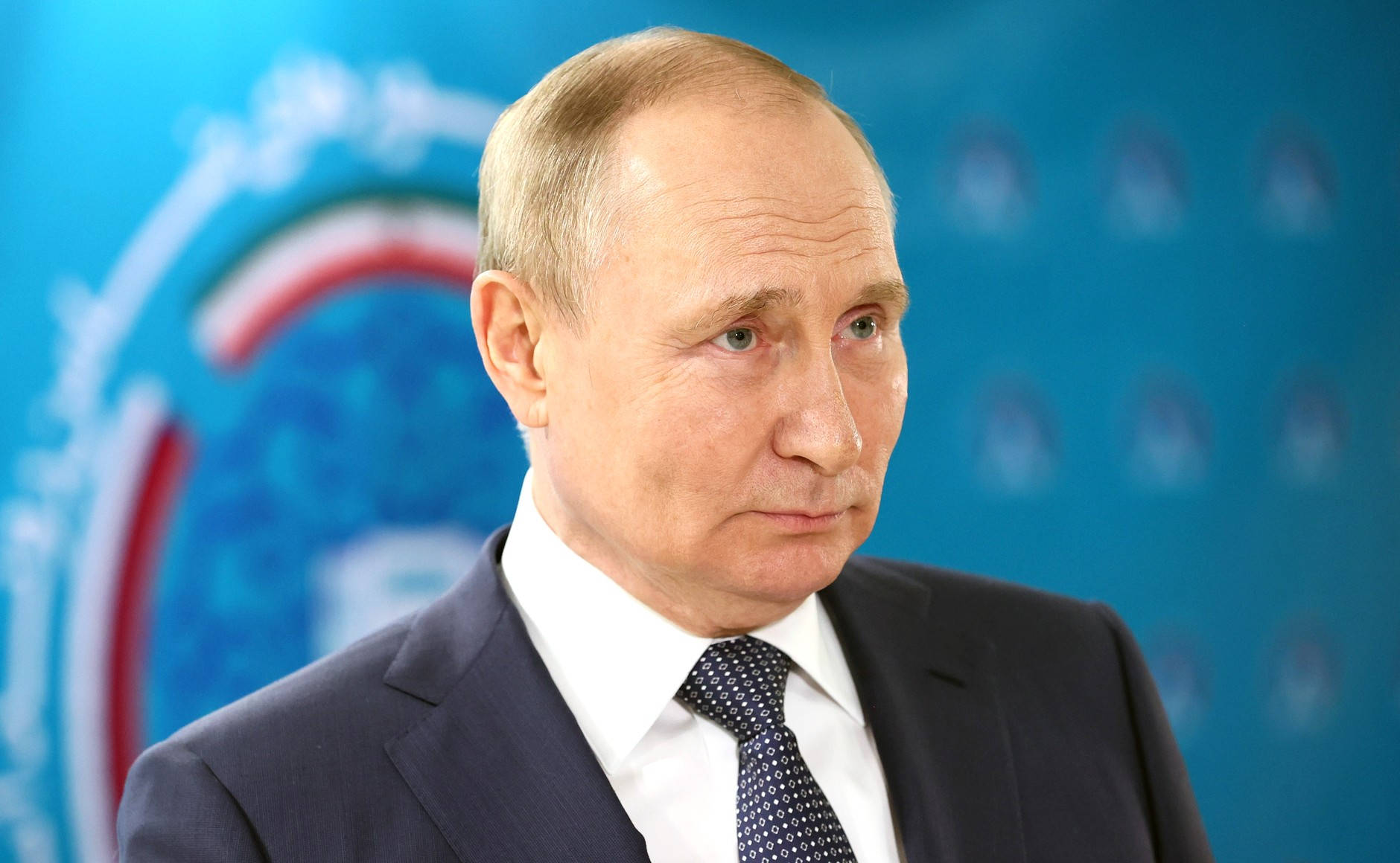 Russian President Vladimir Putin Posing Against A Blurry Blue Backdrop Wallpaper
