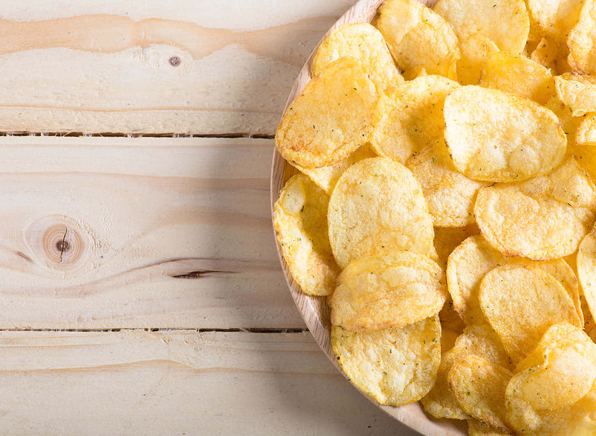 Scrumptious Flat Chips Spilled On The Rustic Wooden Table Wallpaper