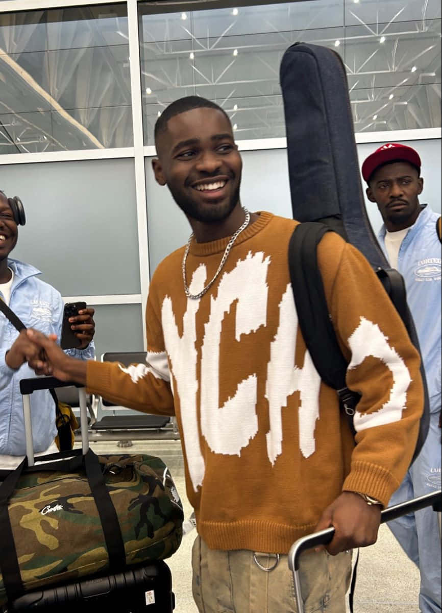 Smiling Man With Guitar Case At Airport Wallpaper